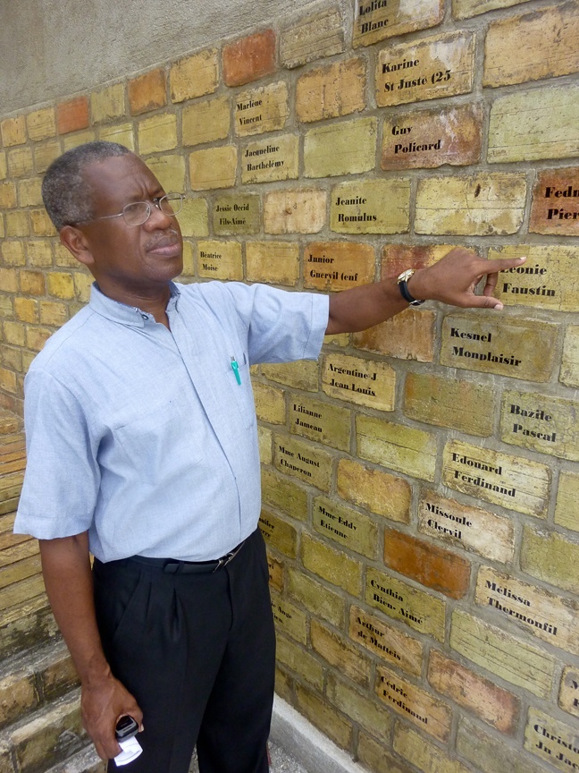 Father Quesnel Alphonse, a Montfort missionary who serves as pastor of the largely destroyed St. Louis King of France Church in Port-au-Prince, points to a brick on the monument that commemorates the victims of the Jan. 12 earthquake, including a fellow Montfort missionary who worked with him at the parish.