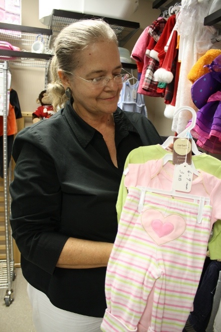 Susana Pando-Taupier holds a baby girl jumpsuit that can be purchased with 3 "mommy dollars" from the South Dade Pregnancy Care Center.