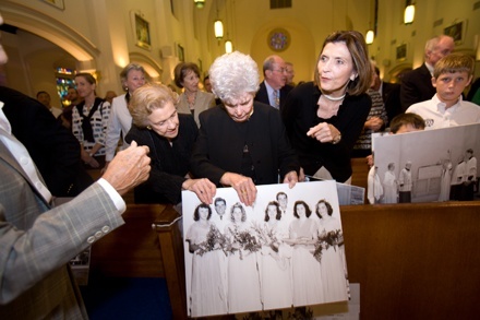 Mary Louisa Smith Scott, Sister Therese Roberts, Ellen Salerno, Parker and Trey West look over historical photographs of St. Anthony Parish and School before the start of the anniversary Mass.