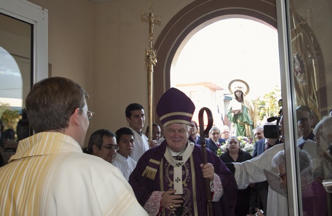 Father Emanuele De Nigris, back to the camera, opens the doors of the church to Archbishop Thomas Wenski, who brings with him the image of St. Cecilia.