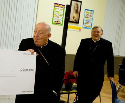 Archbishop Thomas Wenski, right, laughs as Archbishop John C. Favalora holds a check for $ 50,000 in the name of the Archbishop Favalora High School Scholarship Fund to Miami's retired archbishop. The gift was made by the priests of the Archdiocese of Miami.
