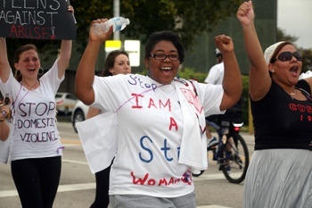 Michelle Bolton, a Johnson and Wales University student, cheers on the cause of stopping domestic violence as she walks on N.E. 125th St., in North Miami