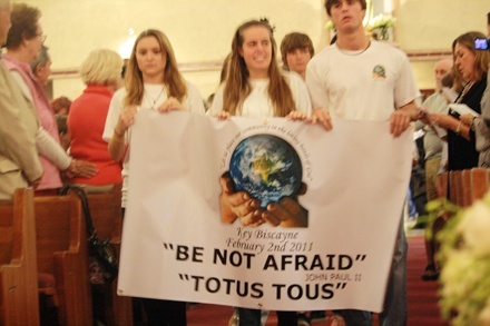 Members of St. Agnes' youth group and the religious education confirmation class carry their banner in the procession.