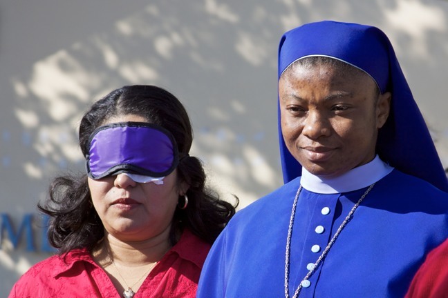Lorena Gomez wears a blindfold and is led by Sister Rose Henry Eboh of the Daughters of Mary Mother of Mercy during an activity where participants are taught how to properly aid a blind person.