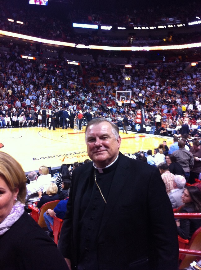 Heat fan from the get-go: Archbishop Thomas Wenski is pictured here at a Jan. 18, 2011 home game against the Atlanta Hawks, during which Heat players wore special shooting shirts featuring a Save Haiti logo designed by South Florida artist Romero Britto. In addition, the Heat coaching staff and broadcasting team wore special Haiti awareness ribbons. The publicity helped raise ,000 for Project Medishare, the non-profit organization founded by Dr. Barth Green and Dr. Arthur Fournier that continues to provide life-saving medical care and community services to the people of Haiti -- at no time more visibly than after the January 2010 earthquake.