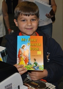 Brayden Franks shows off his first prayer book, which he bought at the conference, where vendors of Catholic material sold books, rosaries and other religious goods.