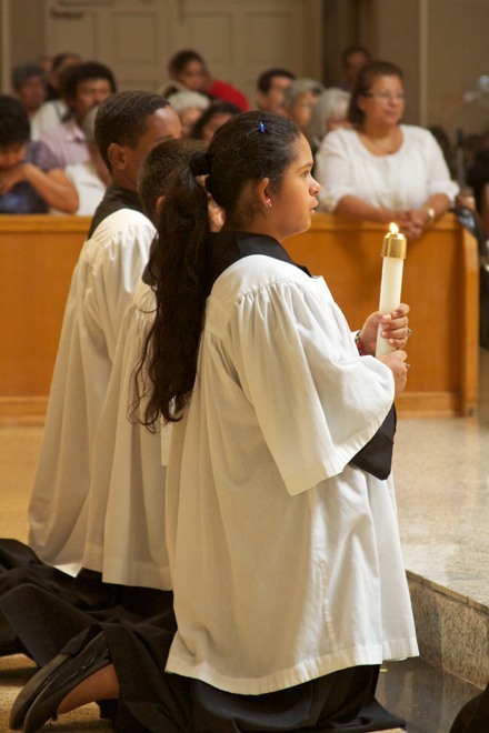 Altar server Gillian Carballo holds a candle during the consecration of the Eucharist on the feast of Corpus Christi at the Church of Corpus Christi in Miami.