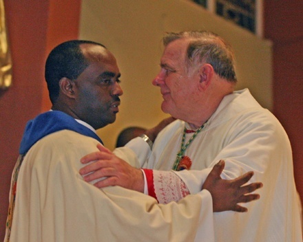 Father Reginald Jean-Mary, Notre Dame d'Haiti's pastor, and Archbishop Thomas Wenski give each other a sign of peace during the Mass.