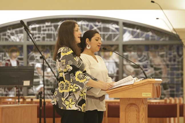 Suzie Arsenault, left, archdiocesan music director, sings the new words of a Mass response with Dora Cardona, a choir member at St. Matthew Parish in Hallandale.