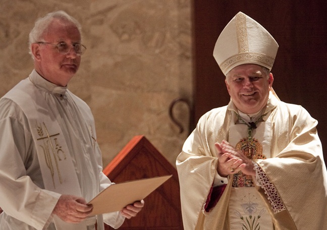 Archbishop Thomas Wenski claps after handing Msgr. Vincent Kelly a blow-up of the check donating ,000 in his name for a needy student at Archbishop Curley-Notre Dame High School. The scholarship will be distributed for five years, at ,000 each year.