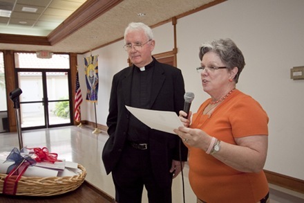 Hope Sadowski, who worked with Msgr. Vincent Kelly for a number of years in the Department of Schools, presents him with dozens of prayer cards and a nearly ,000 gift collected as a retirement present by the archdiocese's schools.