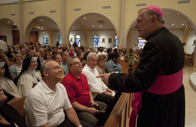 Archbishop Thomas Wenski talks with Synod focus team members before the start of the Mass.