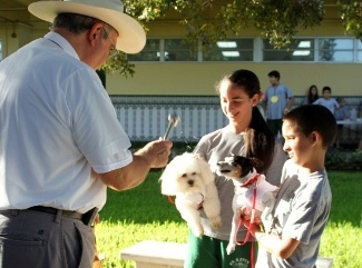 Father Jesus Saldaña, pastor of St. Kevin Parish, blesses the dogs of students, Nicole and Duval Rodriguez.