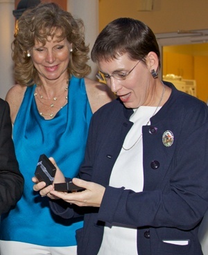 As Jan Rayburn, Safe Environment coordinator looks on, Mara Goldin, parishioner at St. Jerome in Fort Lauderdale, opens a gift given to her by Archbishop Thomas Wenski for her volunteer work for the Archdiocese of Miami.  She has taught more than 100 Virtus training courses during her years as facilitator.