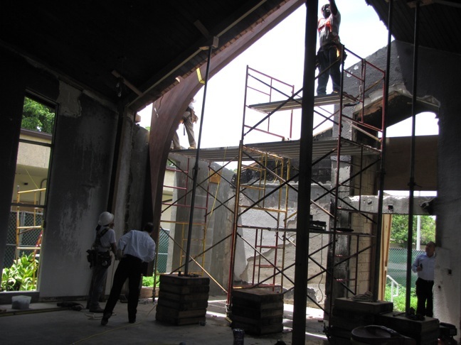 Father Alejandro Rodriguez Artola, pastor of St. Catherine of Siena, watches as the new structural beam is placed on the side of the church that was damaged by fire.