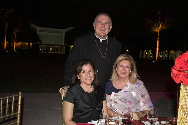 Archbishop Thomas Wenski poses with Reyna Jovel, left, and Danoushka Capponi of St. Joseph Parish in Miami Beach. Behind them is St. Raphael Chapel, the centerpiece building on the campus of St. John Vianney College Seminary.