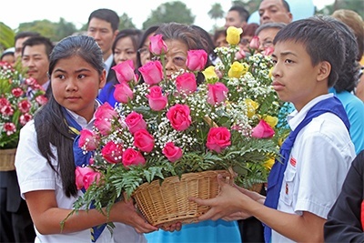 Phuong My Hoang, 13, and Brandon Truong, 13, members of the Vietnamese Apostolate's Eucharistic Youth - wearing blue ties signifying their age group, "searchers" - bring flowers to place before the statue of Our Lady of Vang. The youth wore green for seedlings, yellow for companions, brown for knights and red and yellow stripes for youth leaders.