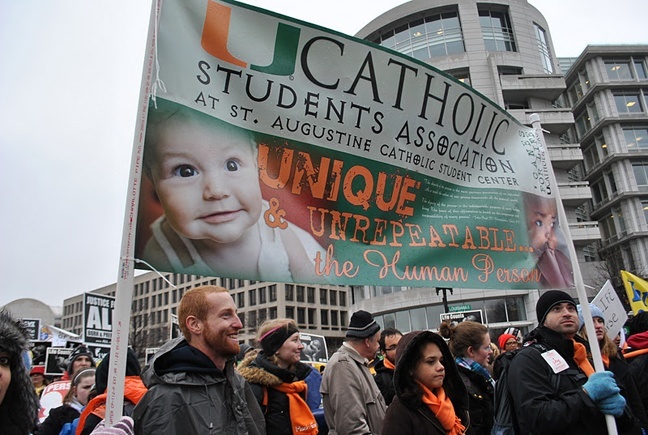 Douglas Ghizzoni carries the banner for UCatholic Campus Ministry at St. Augustine Church in Coral Gables.