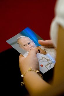 A participant at the Mass at Our Lady of Czestochowa Polish Mission holds one of the holy cards, containing a relic of Blessed John Paul II, which Cardinal Stanislaw Dziwisz handed out to nearly everyone he met in South Florida.