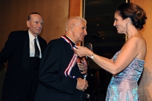 Retired Miami Auxiliary Bishop Agustin Roman receives his Clergy Medallion from MCCJ board chair Patricia A. Thorp as fellow recipient Rabbi Herbert Baumgard looks on.