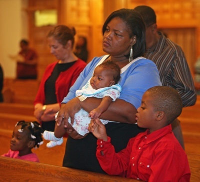 Armand Hercule, 8, touches the hand of his sister, Alexah Hercule, 2, being held by her mother, Loody Hercule. His other sister, Jodie-Leaah, 6, is standing next to her mother.