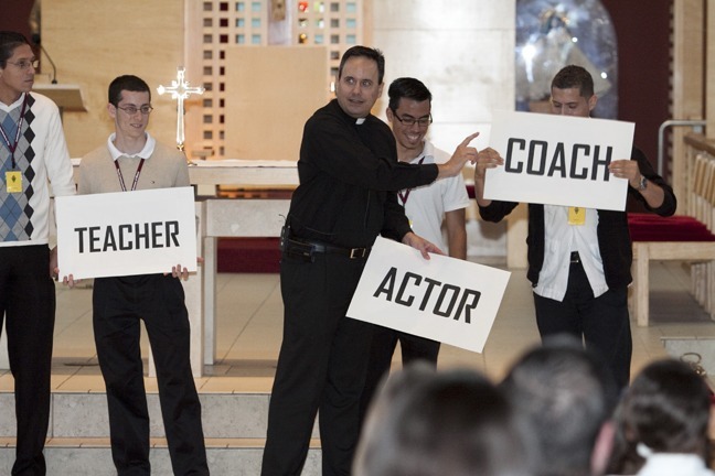 Father David Zirilli, vocations director, leads one of the games played at Focus 11, which revolves around the sixth-graders guessing the profession of the young men on stage.