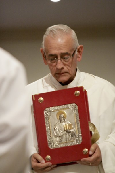Deacon Manolo Perez, who served as Bishop Agustin Roman's master of ceremonies for 28 years, carries the book of the Gospels before proclaiming the Gospel at the funeral Mass.