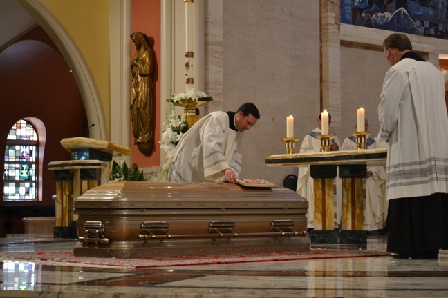 Father Richard Vigoa places the Book of the Gospels atop the casket of Bishop Agustin Roman at the start of the funeral Mass.