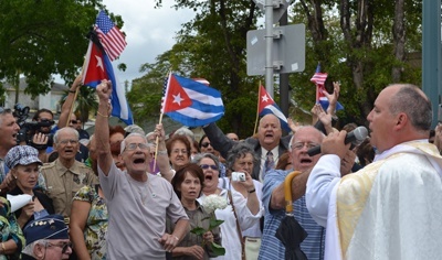 Father Juan Rumin Dominguez, rector of the Shrine of Our Lady of Charity, sings the Cuban national anthem with the crowds gathered at Calle Ocho (S.W. Eighth St.) and S.W. 13th Ave., to pay final tribute to Bishop Agustin Roman.