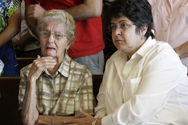 Zoraida Cabrera, 89, is comforted by Sulema Nieves after being overcome with emotion during the noon Mass the day after the death of Bishop Agustin Roman.