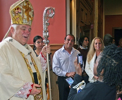 Ajmaani Dort, 8, whose mother was confirmed, tries to take photos of the archbishop using two camera phones at the same time.