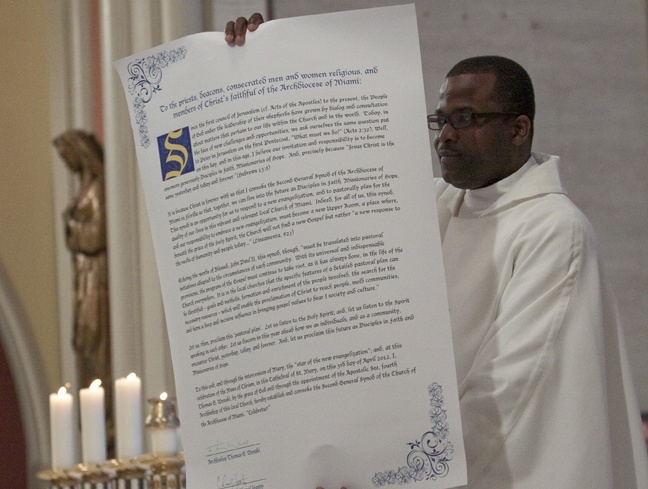 Father Chanel Jeanty, archdiocesan chancellor for canonical affairs, shows the congregation and priests the scroll proclaiming the start of an archdiocesan synod, the second in the history of the Miami archdiocese.