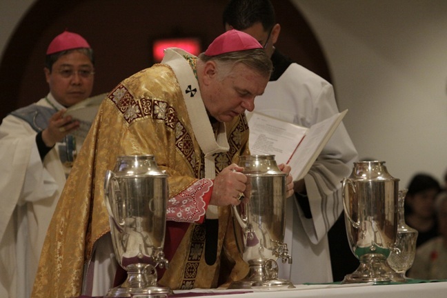 Archbishop Thomas Wenski blows his breath into the oil of chrism, consecrating it for use at confirmations, baptisms and ordinations.