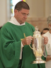 A deacon brings up the the oil of catechumens which is used in baptisms.