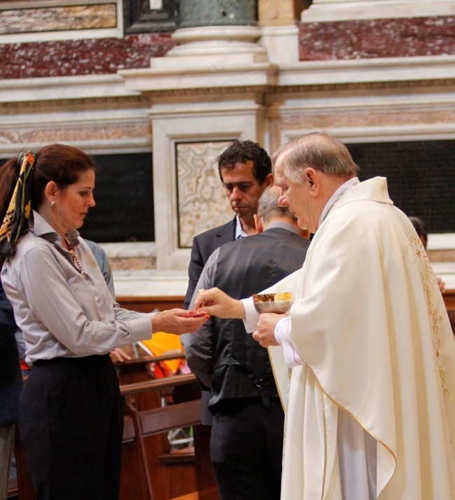 Pilgrim Vicky Yardley of Assumption Church receives Holy Communion from Archbishop Thomas Wenski.