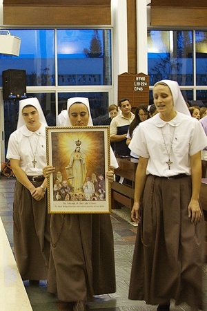 Members of the Servants of the Pierced Hearts of Jesus and Mary carry the image of the Virgin Mary in procession at the beginning of the Mass.