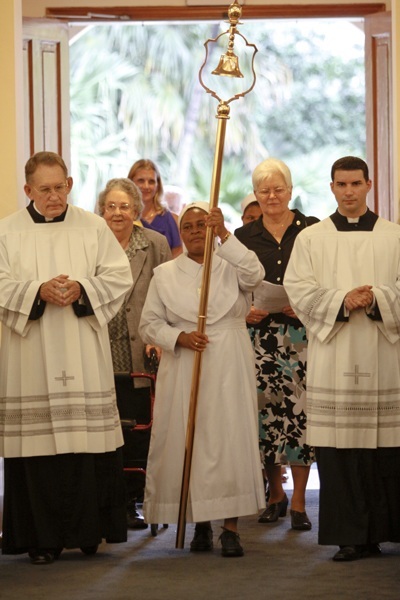 Sister Mary Silvestry Mushi, of the Sisters of the Holy Spirit who now work at the parish and school, carries the tintinnabulum (bell) into the Basilica of St. Mary Star of the Sea. Behind her are two representatives of the Sisters of the Holy Names of Jesus and Mary who staffed the parish and school for 115 years. From left, Sister Theresa Cecilia Lowe and Sister Dolores Wehle, who both taught at the school.