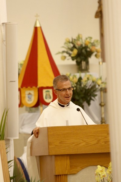 Father John Baker addresses his parishioners at the end of the Mass. Behind him is the ombrellino, one of the insignia of a basilica.