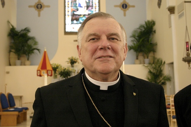 Archbishop Thomas Wenski poses for a photo in front of the altar of the Basilica of St. Mary Star of the Sea. At left, behind him, is the ombrellino, one of the insignia of a basilica.
