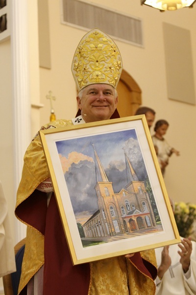 Archbishop Thomas Wenski shows off the first print of a specially commissioned painting of the new basilica, created by Key West artist Richard Matson.