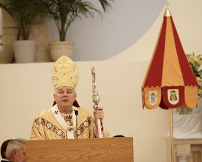 Archbishop Thomas Wenski preaches the homily, framed by one of the insignia of the basilica, the ombrellino.