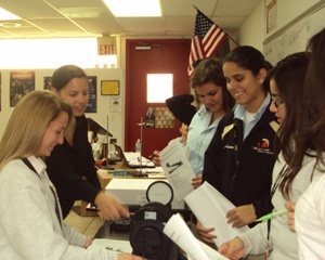 Msgr. Pace physics and chemistry teacher Juliette Victoria, second from left, guides her students in an optics bench experiment.
