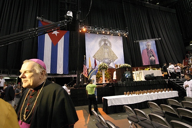 Enmarcado por una gigantesca bandera cubana y fotograf�as de la Virgen de la Caridad y Mons. Agustin Roman, el Arzobispo Thomas Wenski habla con la prensa antes de comenzar la misa.