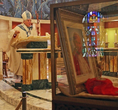 Archbishop Thomas Wenski preaches the homily as a photo of Pope John Paul II and a blood relic are displayed in the foreground.