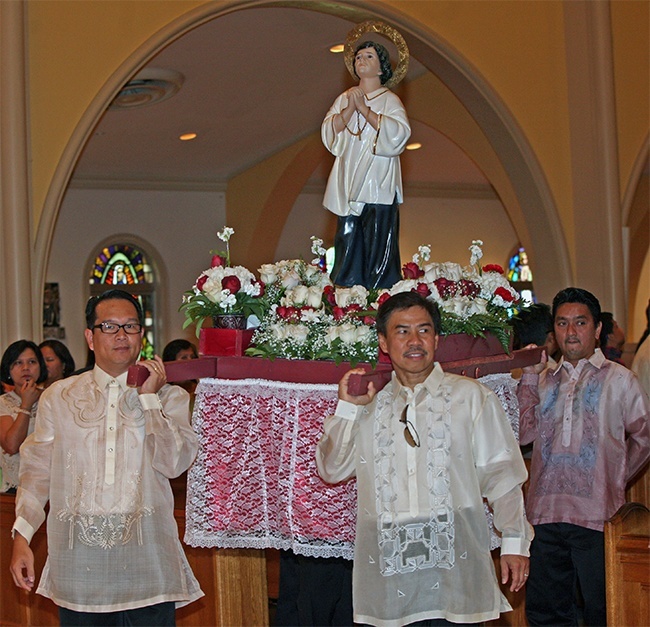 Erwin Caampued and Jun Padua help carry the statue of San Lorenzo Ruiz of Manila into St. Mary Cathedral.