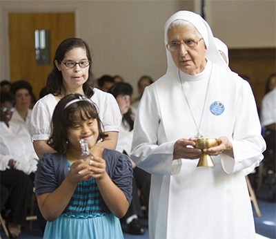 Taking up the offertory during the Mass, clockwise from left front: students Mary Isabella Gonzalez and Joelyn Rodriguez and Sister Paola Nofori of the Sisters of St. Joseph Benedict Cottolengo.