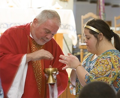 Father Curtis Kiddy gives Communion to Marian Center student Ashley Acocella.