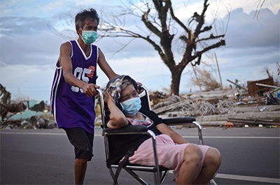 A man and a woman in a wheelchair wear surgical masks to protect themselves in Tacloban City on November 14, 2013 in Tacloban, Philippines.
