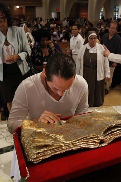 A young man venerates the relic of Pope John Paul II.