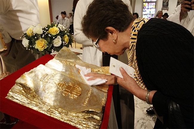 A woman touches a handkerchief to the relic of Pope John Paul II during its first stop in the archdiocese, at St. Mary Cathedral.